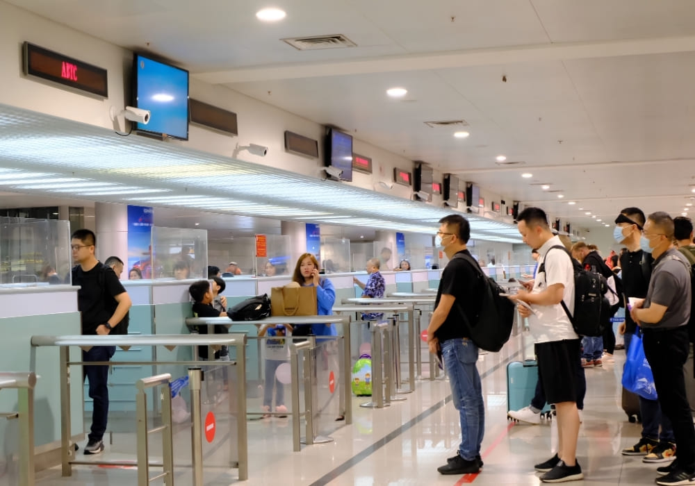 Singapore travelers entering Vietnam complete immigration procedures at passport control counters.
